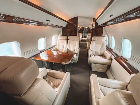 Luxurious interior of a private jet showcasing leather seating and elegant wooden trim.