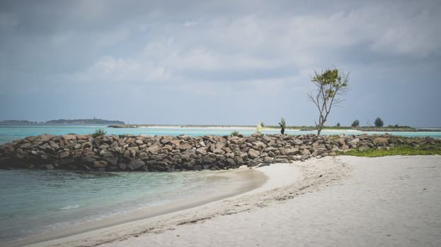 Tranquil beach landscape at Maafushi island with rocky shoreline in Maldives.