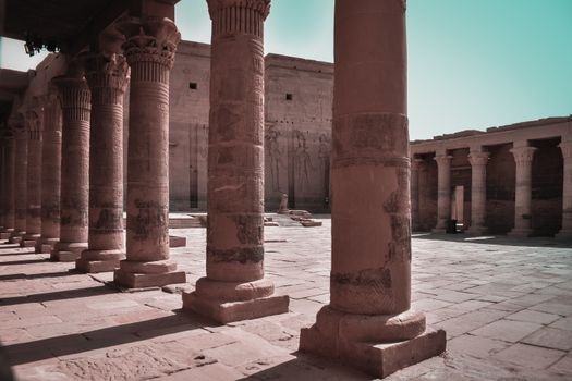 Majestic columns in an ancient Egyptian temple courtyard, Aswan, showcasing intricate carvings.
