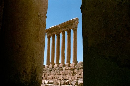 View of ancient Roman columns framed between stone walls, evoking a vintage aesthetic.