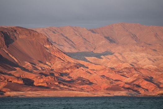 A breathtaking view of red rock formations surrounding Lake Mead at sunset, showcasing nature's beauty.