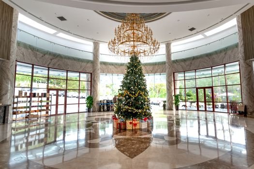 Spacious hotel lobby featuring a beautifully decorated Christmas tree and elegant chandelier.