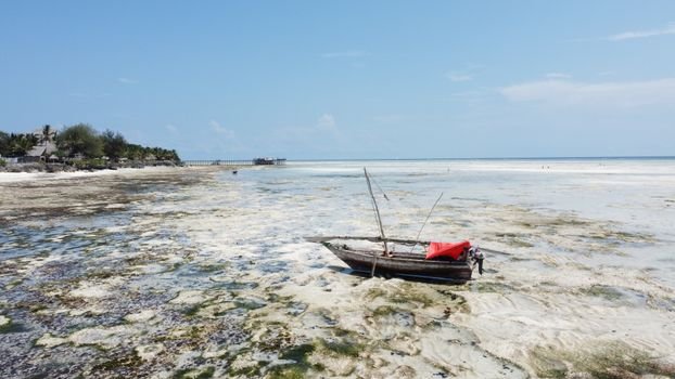 A stranded fishing boat at low tide on the beaches of Zanzibar, Tanzania.