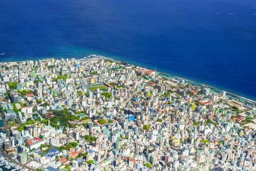 Colorful aerial view of Malé, Maldives showcasing cityscape and ocean coastline.