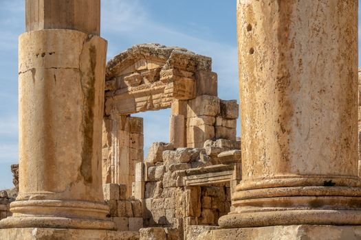 Close-up of ancient Roman ruins showcasing large stone pillars under a blue sky.