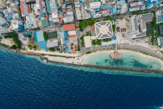 A top-down aerial view of a vibrant coastal city and clear blue ocean.