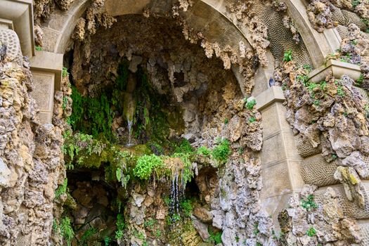 A detailed stone archway with cascading moss and a small waterfall.