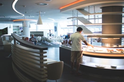Stylish airport lounge with buffet and seating, featuring sleek interior design and contemporary furniture.
