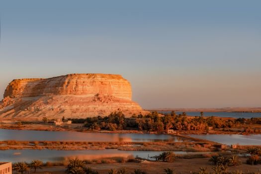 Captivating desert landscape with a majestic mountain and tranquil lake under a blue sky.