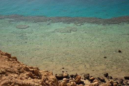 Scenic view of a tranquil beach with clear aqua waters and rocky shoreline.