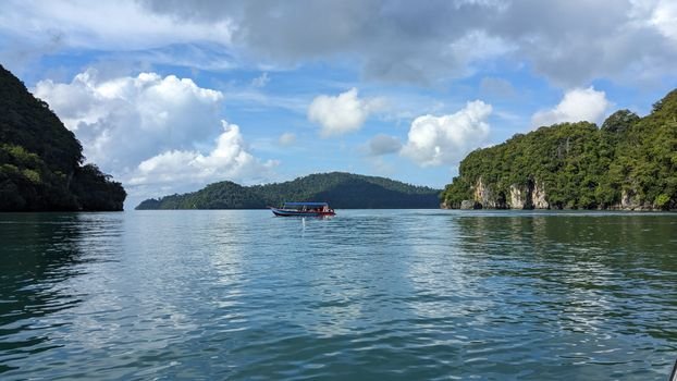A tranquil boat ride on Langkawi, Malaysia, showcasing lush islands and clear waters under a bright sky.