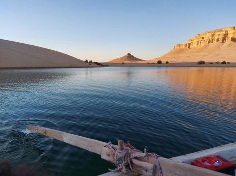 Peaceful desert lake view with unique rock formations during the daytime.