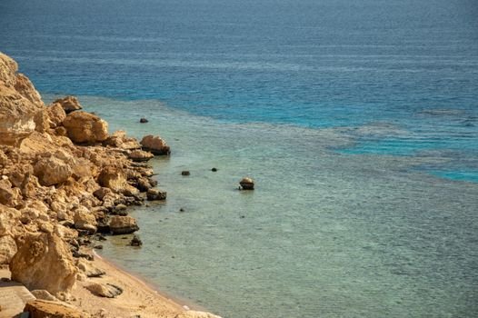 Beautiful scenic view of a rocky shoreline meeting clear blue ocean waters.