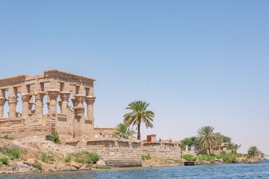 Ancient ruins of Philae Temple by the Nile River under a clear blue sky.