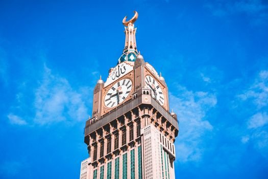 Stunning view of the iconic Abraj Al Bait Clock Tower against a vibrant blue sky in Mecca, Saudi Arabia.