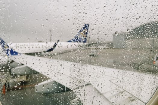 Raindrops on airplane window with a view of the airport in Almaty, Kazakhstan.