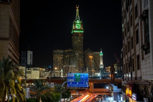 Illuminated view of Makkah Royal Clock Tower at night in the cityscape.